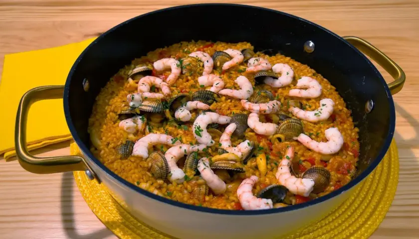 Arroz con gambones y almejas en paellera, listo para disfrutar.