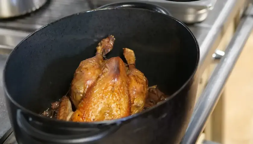 Un poulet rôti doré dans une cocotte. Quel vin rouge avec du poulet ? Un Pinot Noir léger ou un Beaujolais fruité serait parfait.