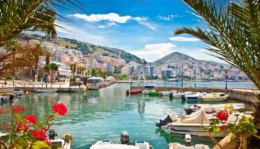 Albania, gdzie najpiękniej! Widok na port z łodziami i kolorowe budynki na wzgórzu.