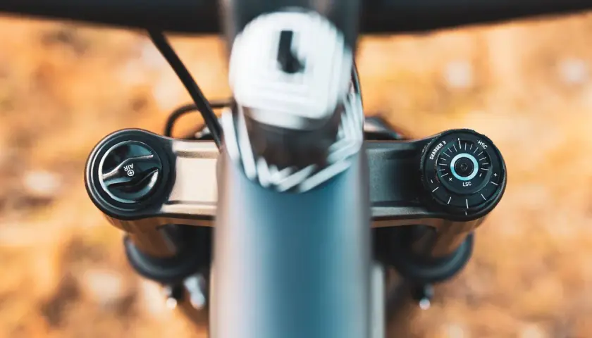 Close-up of a RockShox Pike fork's top caps, showing the "AIR" and "CHARGER 3" adjustments. The weight of this fork is a key factor for trail riders.
