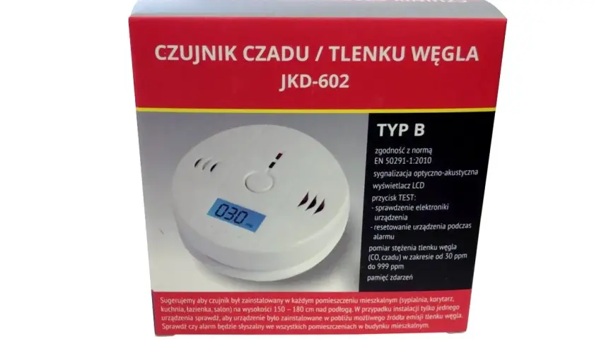 Biały czujnik czadu z wyświetlaczem LCD pokazującym "030" na tle czerwonego opakowania.