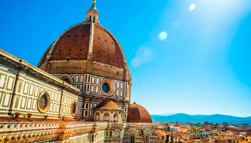 Majestatyczna katedra Santa Maria del Fiore we Florencji, z jej charakterystyczną kopułą, góruje nad miastem w słoneczny dzień.