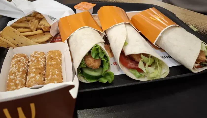 Trzy mcwrap klasyczny z kurczakiem, warzywami i sosem. Obok frytki i paluszki serowe. Idealny zestaw na szybki posiłek, z uwzględnieniem kcal.