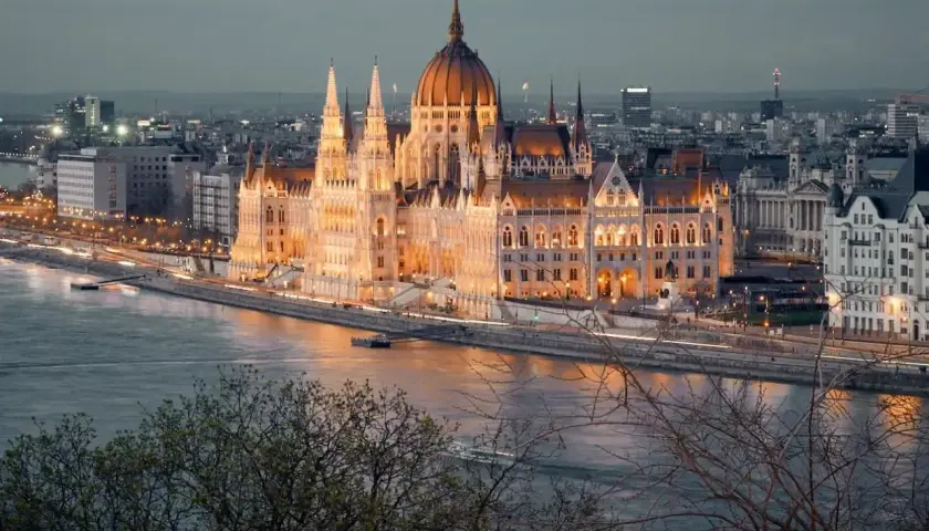 Wspaniały Parlament w Budapeszcie o zmierzchu, oświetlony i odbijający się w Dunaju. Obowiązkowy punkt, co zobaczyć w Budapeszcie.