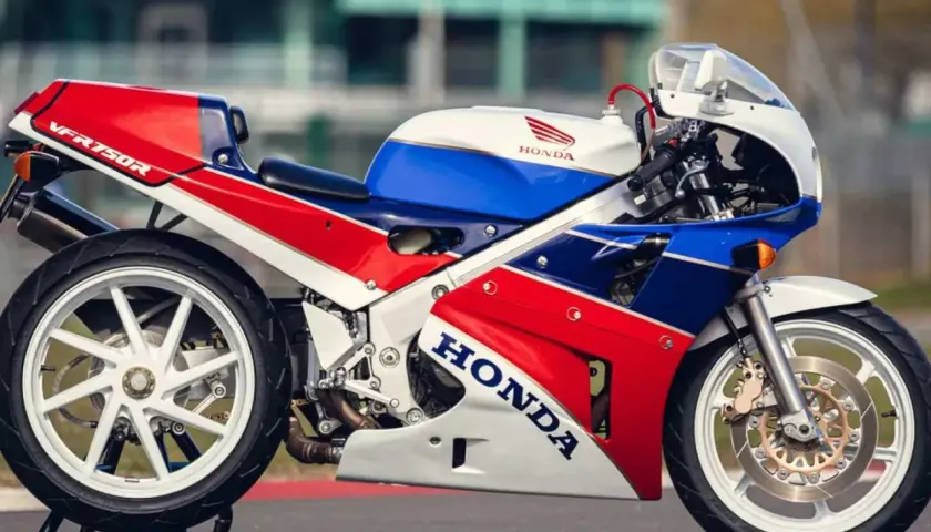 La icónica Honda RC30 VFR750R, con su distintivo tricolor rojo, blanco y azul, lista para la pista.