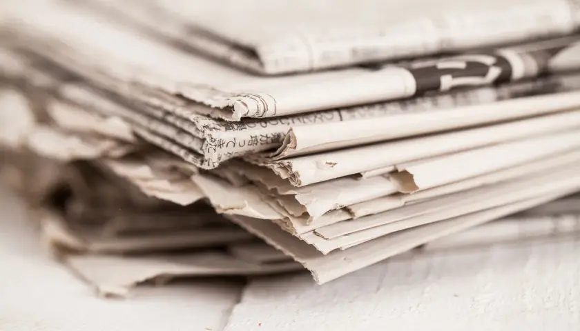 Stos gazet, gotowy do wrzucenia do pojemników na makulaturę.
