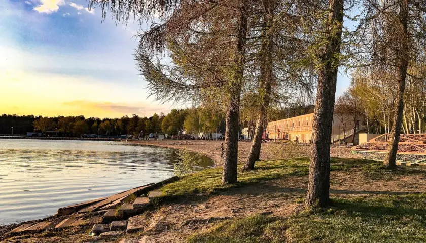 Zachód słońca nad jeziorem, plaża i drzewa. Skorzęcin atrakcje turystyczne czekają na odkrycie.