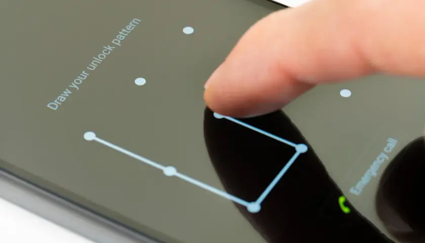 Palec rysuje wzór na ekranie telefonu, pokazując, jak odblokować telefon.
