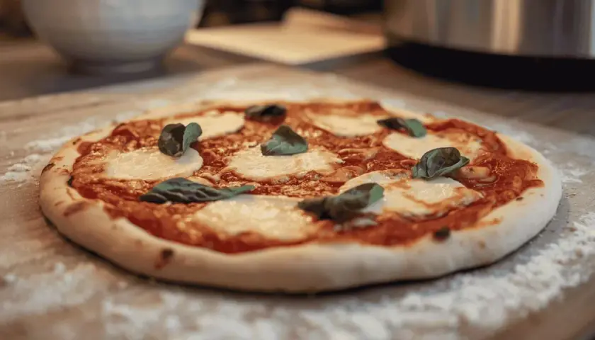 Une délicieuse pizza Margherita, avec sa pâte à pizza maison, prête à être dégustée. Un vrai délice pour les amateurs de pain et de bonnes choses.