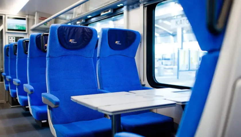 Wygodne, niebieskie siedzenia w przedziale konduktorskim PKP Intercity. Czekają na pasażerów, by zabrać ich w podróż.