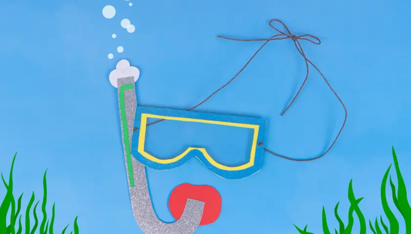 Buntes Papier-Bastelset: Taucherbrille malen mit Schnorchel und roten Lippen, umgeben von Seegras und Luftblasen.