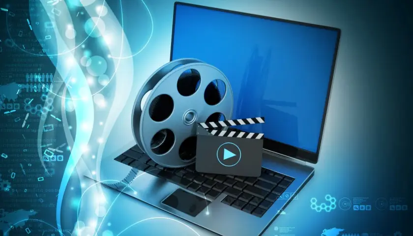 Laptop z kliszą filmową i klapsem, symbolizujące odtwarzanie multimediów. Idealne do obsługi plików dzięki K-Lite Codec Pack.