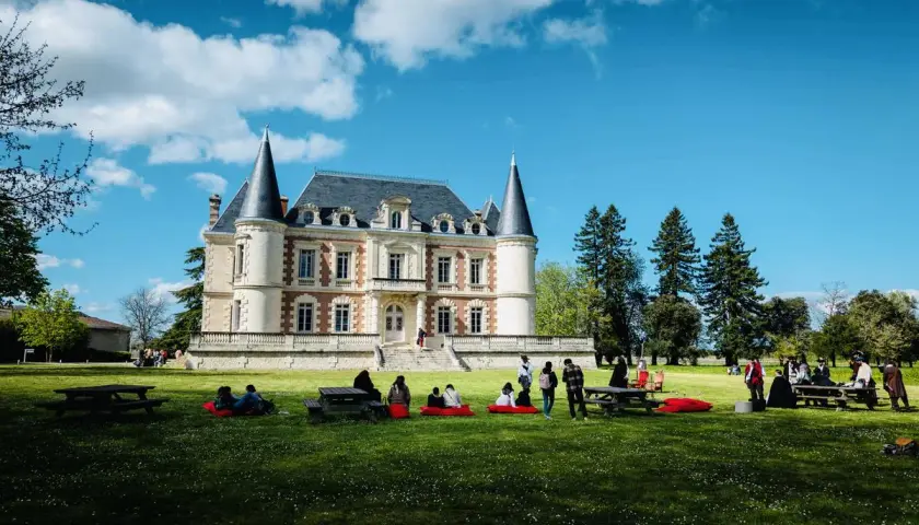 Visite d'un magnifique château dans le Médoc, avec des gens profitant du soleil sur la pelouse.