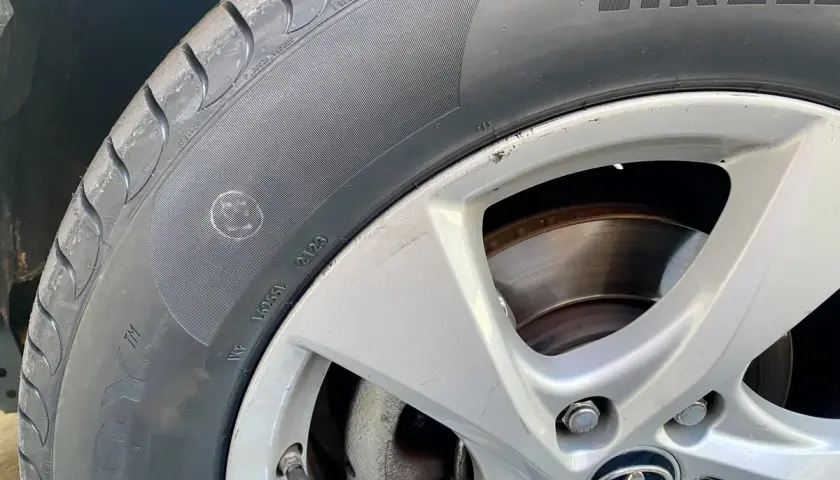 Un neumático Pirelli con un punto amarillo, marca de fábrica, y un pequeño círculo con una cara sonriente en el flanco.
