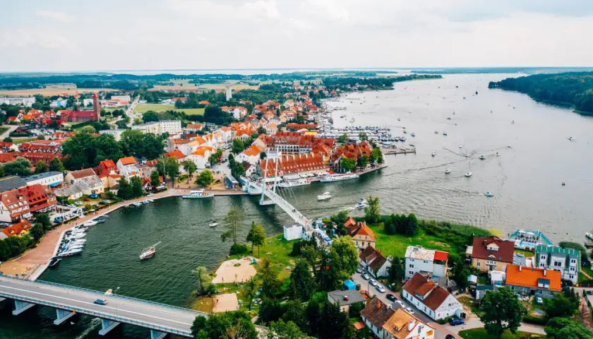 Malownicze miasta na Mazurach z widokiem na jezioro i liczne łodzie.