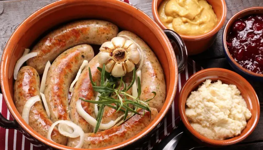 Pyszna biała kiełbasa pieczona w cebuli i musztardzie, podana z chrzanem i żurawiną.