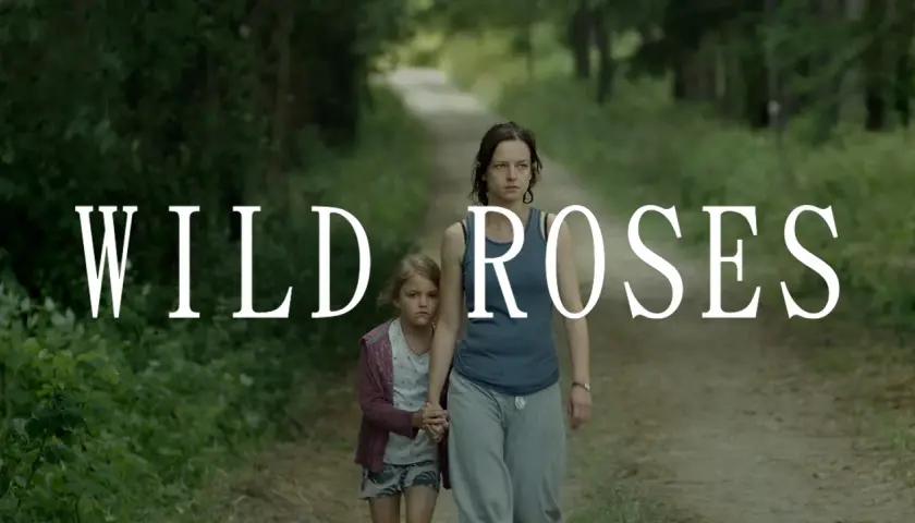 Kobieta i dziewczynka idą ścieżką w lesie. Napis "WILD ROSES" sugeruje, że to kadr z filmu.