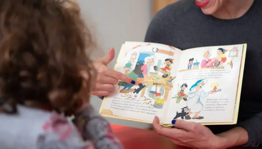 Donna legge un libro illustrato a un bambino, un momento di apprendimento che supporta il rinnovo certificazione DSA.