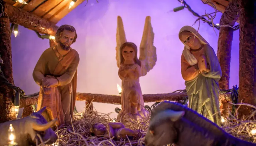 Portal de Belén manualidades: figuras de San José, la Virgen María, un ángel, el Niño Jesús, un buey y una mula, iluminados con luces navideñas.
