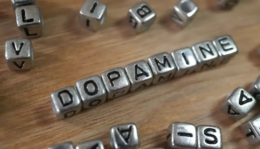 Cubos plateados forman la palabra "DOPAMINE". Descubre cómo aumentar tu dopamina para sentirte mejor.