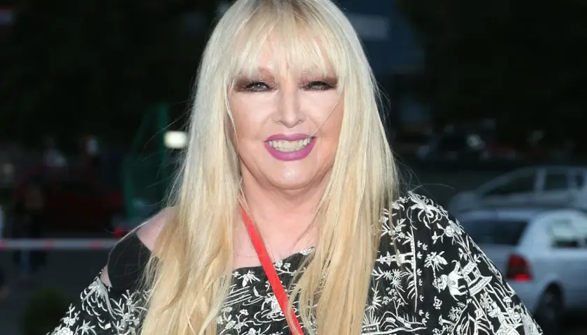 Maryla Rodowicz w czarno-białej sukience z ozdobnym wzorem, z długimi blond włosami i makijażem.