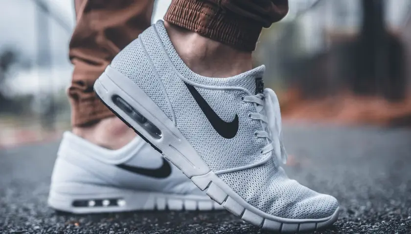 Białe buty Nike na siateczkowanej cholewce, z czarnym logo. Dowiedz się, jak wyczyścić białe buty, by wyglądały jak nowe.