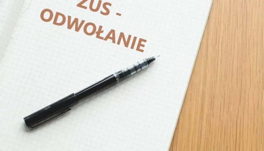 Notatka z napisem "ZUS - ODWOŁANIE" i czarny długopis na kratkowanym papierze.
