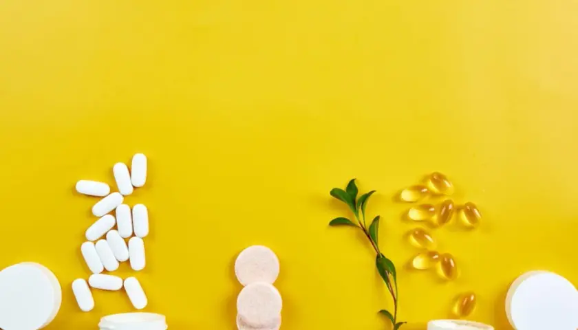 Weiße Pillen, Kapseln und Brausetabletten auf gelbem Grund. Informationen zu Chondroitin Nebenwirkungen sind wichtig, bevor man solche Präparate einnimmt.
