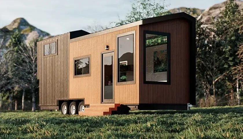 Tiny house sur roues dans un paysage verdoyant. La question "un particulier peut il acheter une maison en zone agricole" se pose face à ce type d'habitat.