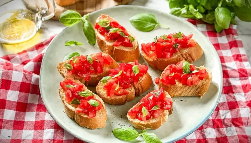 Frische italienische Crostini mit Tomaten und Basilikum auf einem Teller, garniert mit frischen Basilikumblättern.