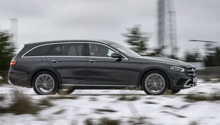 Mörkgrå Mercedes All-Terrain wagon kör på en snöig väg, redo för alla utmaningar.