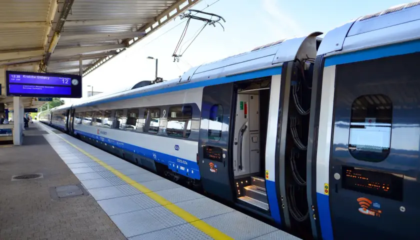 Pociąg PKP Intercity na peronie, tablica informacyjna pokazuje odjazd do Krakowa. Czekam na pociąg, mam nadzieję, że nie będzie awarii PKP.