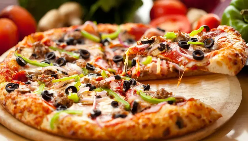 Idealny dzień pizzy! Gorąca, ciągnąca się pizza z mnóstwem dodatków: oliwkami, papryką, cebulą i mięsem.