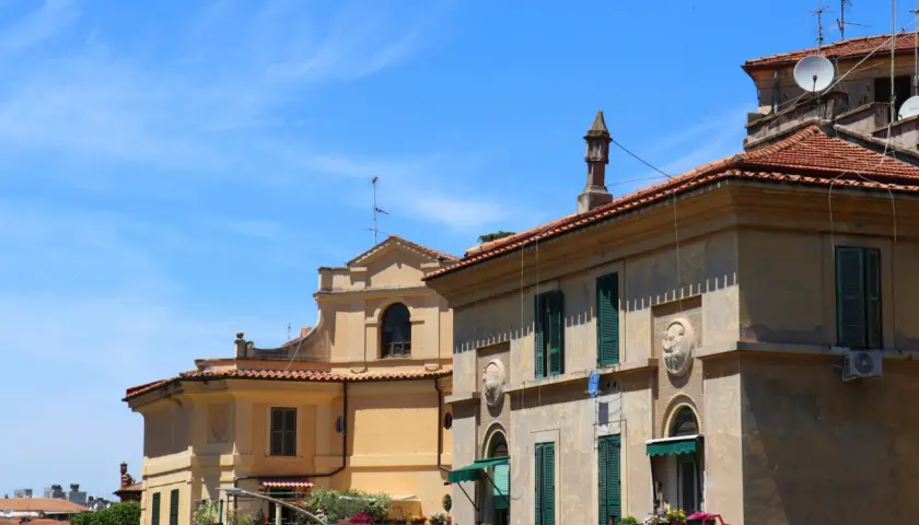 Edifici storici con tetti rossi e finestre verdi a Garbatella, un quartiere romano da scoprire.