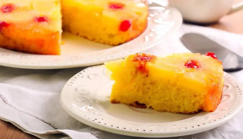 Una fetta di torta ananas, con la sua base dorata e la copertura di frutta caramellata, pronta per essere gustata.
