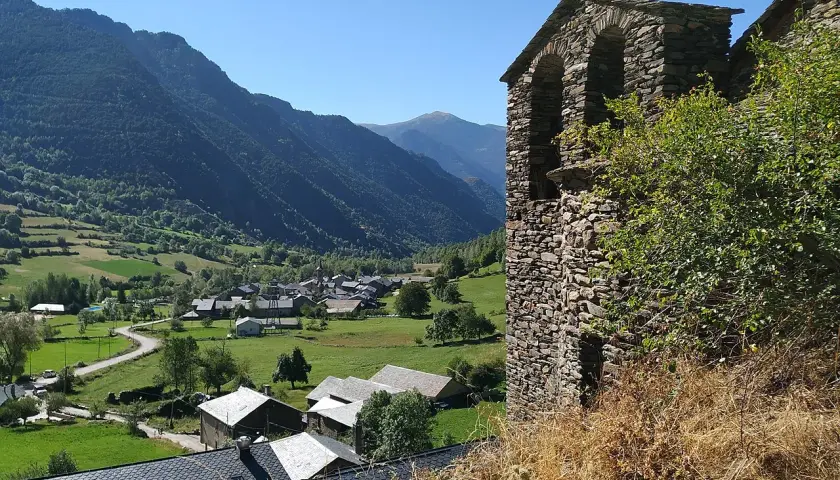 Vista del pueblo de Vall Ferrera con su campanario de piedra y montañas verdes al fondo.
