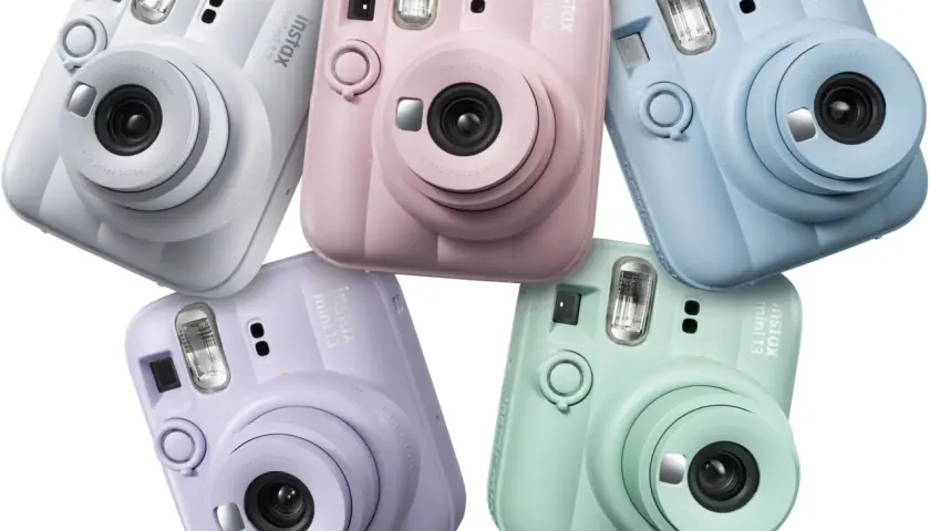 Pięć aparatów Instax Mini 13 w pastelowych kolorach: białym, różowym, niebieskim, fioletowym i miętowym.