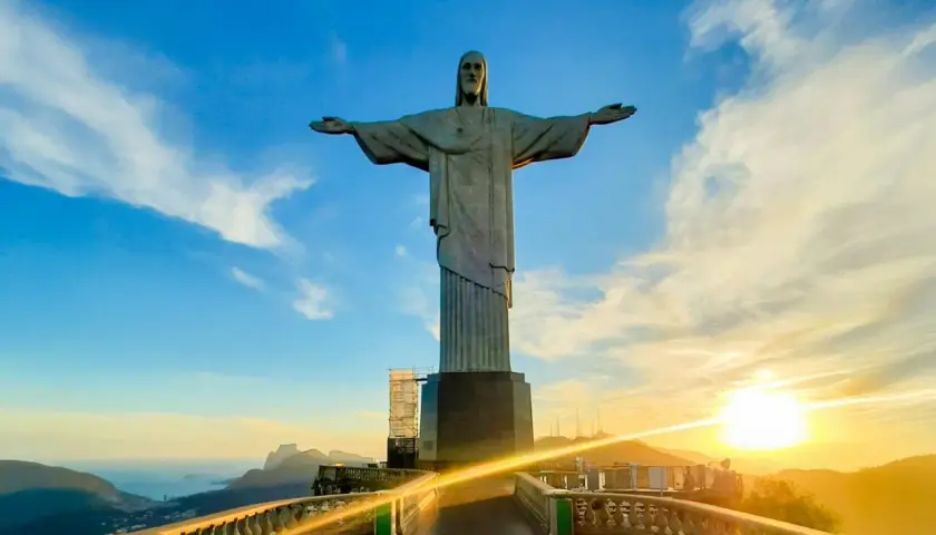 Christusstatue in Brasilien mit weit ausgebreiteten Armen, die den Sonnenuntergang über Rio de Janeiro überblickt.