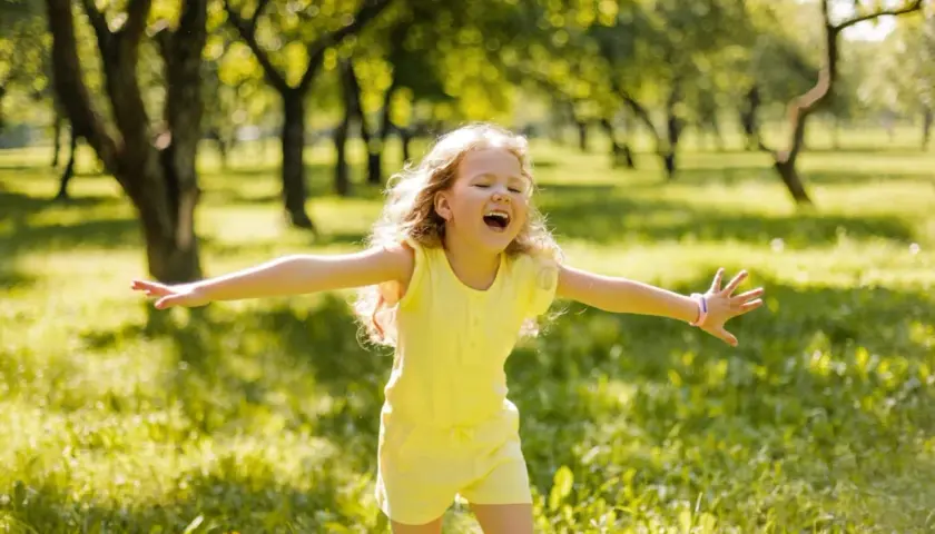 Niña feliz en un parque, disfrutando del sol. Su alegría refleja la autoestima en niños de 9 a 12 años.