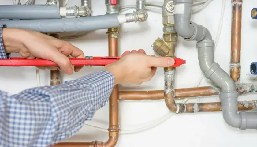 Instalator dokręca kluczem zawór przy punkcie hydraulicznym. Sprawdź punkt hydrauliczny cena robocizny.