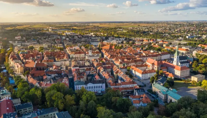Widok z lotu ptaka na zabytkowe centrum Kalisza, najstarszego miasta w Polsce, z charakterystyczną czerwoną dachówką i zielenią drzew.