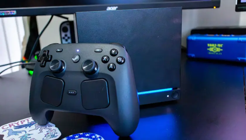 Ein schwarzer Steam Controller 2 liegt vor einem dunklen Gaming-PC.
