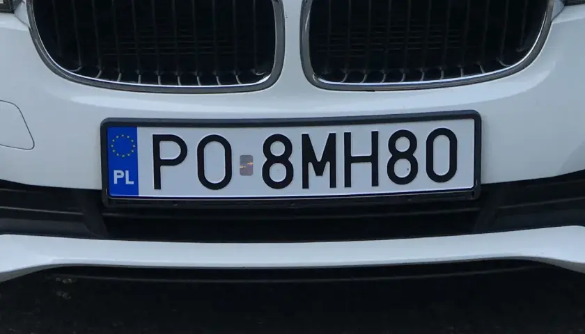 Białe auto z tablicą rejestracyjną PO 8MH80.