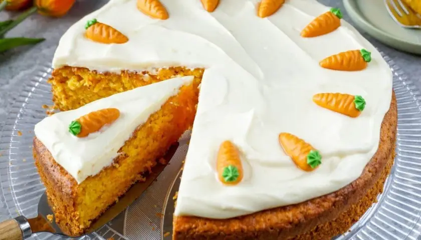 Ein saftiger Karottenkuchen mit weißem Zuckerguss und kleinen Marzipanmöhren, perfekt als Geburtstagskuchen für Kinder.