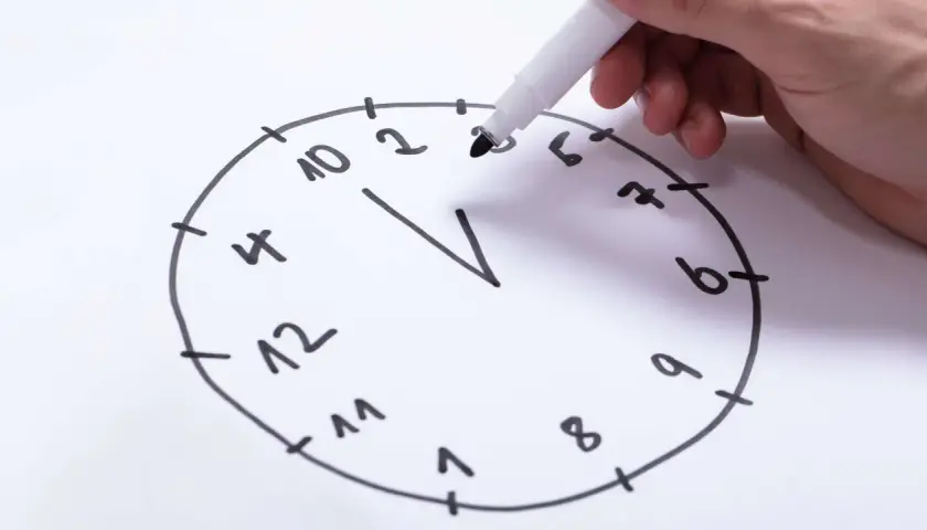 Hand zeichnet eine Uhr für einen Uhrentest Demenz. Die Zahlen sind unvollständig und die Zeiger fehlen.