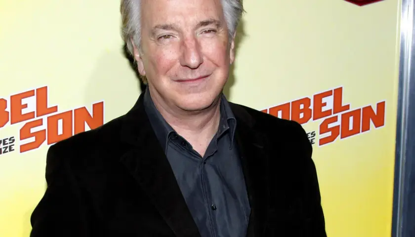 Alan Rickman, uśmiechnięty, w czarnym garniturze, na tle napisu "BEL SON". Może wspominał swoje dzieciństwo?