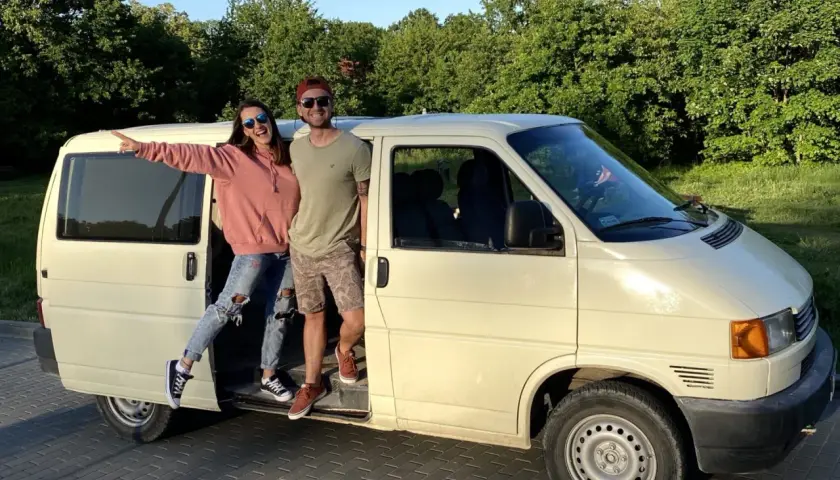 Para młoda pozuje przy swoim t4 camperze, gotowa na przygodę.