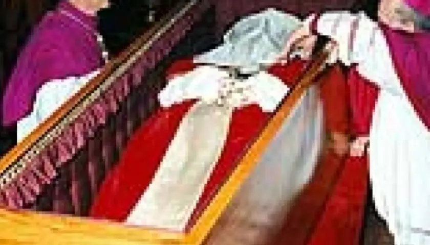 Würdenträger bei der Umbettung von Johannes Paul II. im Sarg, der mit rotem Stoff und weißen Bändern geschmückt ist.