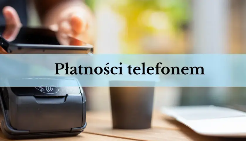 Zbliżenie na terminal płatniczy i kubek kawy. Dłoń trzyma smartfon, gotowa do płatności telefonem.