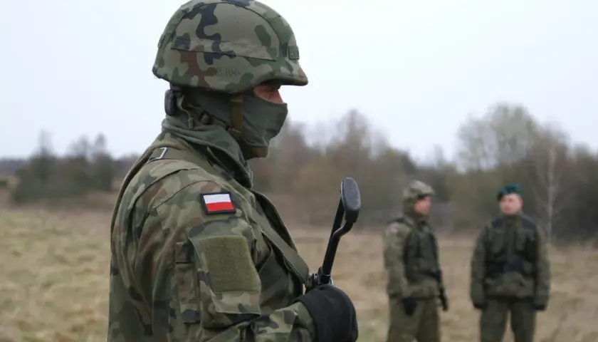 Żołnierz w kamuflażu, z polską flagą na ramieniu, gotowy do służby. Czy to zapowiedź podwyżki w wojsku w 2026 roku?